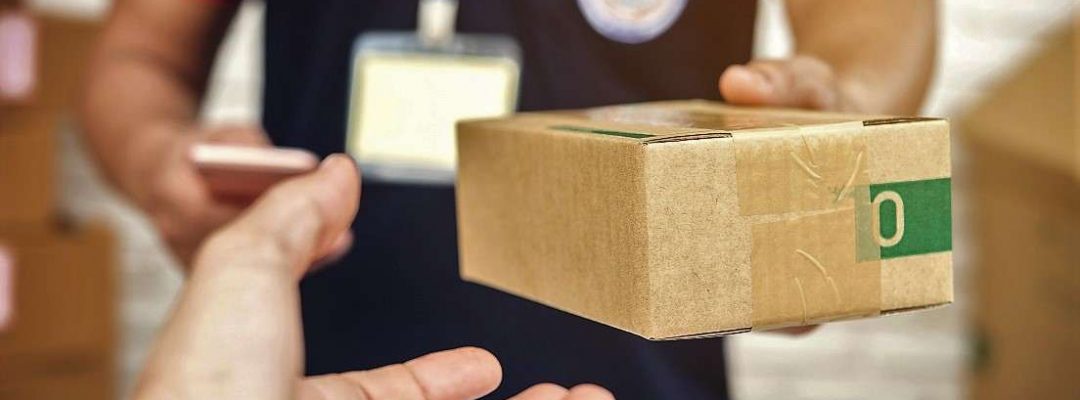 delivery man smiling and holding a cardboard box